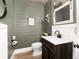 Modern bathroom with a wood vanity, white sink, toilet, decorative mirror, and green wooden wall paneling at 1392 W Caley Ave, Littleton, CO 80120