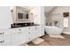 A modern bathroom features a soaking tub and double vanity with black countertops and white cabinets at 1392 W Caley Ave, Littleton, CO 80120