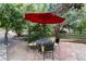 Relaxing patio area with a red umbrella and a table with seating surrounded by lush landscaping at 1392 W Caley Ave, Littleton, CO 80120