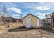 Backyard view of a yellow shed with a white door and surrounding trees at 13581 Sable Blvd, Brighton, CO 80601