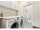 Laundry room featuring modern washer and dryer with overhead cabinets and access to a stylishly tiled powder room at 6901 E 12Th Ave, Denver, CO 80220