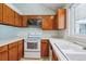 Functional kitchen featuring a white oven, wood cabinets, and a sink with a bright window above at 262 S Nome St, Aurora, CO 80012