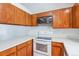 Functional kitchen featuring wood cabinetry and a white range oven with microwave at 262 S Nome St, Aurora, CO 80012