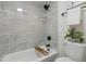 Modern bathroom featuring sleek marble tiling, black hardware, and a bright bathtub with shower at 6193 Holland St, Arvada, CO 80004