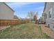 Spacious backyard with green grass, a wooden fence, a deck, and garden space at 13472 Monroe St, Thornton, CO 80241