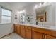 Bright bathroom featuring dual sinks, wood cabinets, quartz countertop, and a window for natural light at 13472 Monroe St, Thornton, CO 80241