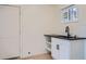 A utility sink with a black countertop, white cabinet, open shelves, and a small window at 851 S Umatilla Way, Denver, CO 80223