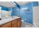 Bright bathroom with wood cabinets, a framed mirror, and blue painted walls at 11545 E 119Th Ave, Commerce City, CO 80640