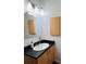 Bathroom vanity with black counter, white sink, bright lighting, and wood-look cabinet at 500 30Th St # 5, Denver, CO 80205