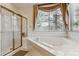 Bright bathroom featuring a tiled corner tub under a window and a glass-enclosed shower at 3860 S Elkhart St, Aurora, CO 80014