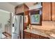 Kitchen detailing wooden cabinetry, granite counters, stainless steel refrigerator, and a window at 2836 Cherry St, Denver, CO 80207