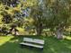 Park bench on a grassy lawn near a calm pond, shaded by large, mature trees at 13635 E Bates Ave # 406, Aurora, CO 80014