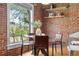 Cozy dining area with exposed brick wall, large window, modern table and chairs, creating a warm and inviting space at 624 E 18Th Ave # 3, Denver, CO 80203