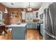 Stylish kitchen featuring brick accent wall, stainless steel appliances, and a gray center island with white countertop at 624 E 18Th Ave # 3, Denver, CO 80203