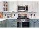 Close-up of the modern kitchen features stainless appliances, quartz countertops, and blue-gray cabinets with a backsplash design at 624 E 18Th Ave # 3, Denver, CO 80203
