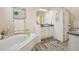 Bright bathroom featuring a soaking tub, white cabinets, and modern vanity with double sinks at 2601 S Kipling Ct, Lakewood, CO 80227