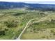 Expansive aerial view of a large parcel with roads, trees and rolling hills, and mountains in the distance at 8821 S Perry Park Rd, Larkspur, CO 80118