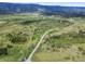Aerial view of a large parcel with roads, trees and rolling hills, and mountains in the distance at 8821 S Perry Park Rd, Larkspur, CO 80118