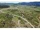 Expansive green landscape with a winding road, dotted with trees and shrubs, set against distant mountain views at 8821 S Perry Park Rd, Larkspur, CO 80118