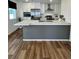 A modern kitchen boasts stainless steel appliances and white cabinets complementing the light countertops and wood flooring at 5060 N Walden Way, Denver, CO 80249