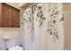 Cozy bathroom featuring a floral shower curtain, wood cabinets, and white beadboard paneling at 16602 E Gunnison Pl, Aurora, CO 80017