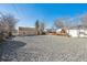 Gravel backyard featuring mature trees, storage buildings, and clear blue skies above at 1934 Macon St, Aurora, CO 80010