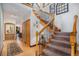 Inviting foyer with hardwood floors and a staircase featuring wrought iron spindles and wood banister at 1250 Oneida St, Denver, CO 80220