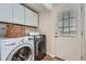 Well-lit laundry room with front-loading washer and dryer, storage cabinets, and exterior door at 5855 Rustic Knolls Dr, Boulder, CO 80301