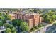 Low-rise brick apartment building with lush trees, surrounding streets, and other commercial buildings at 1630 N Clarkson St # 110, Denver, CO 80218