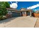 Inviting home featuring a two-car garage, brick accents, and a well-kept lawn under a blue sky at 16257 E 105Th Cir, Commerce City, CO 80022