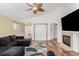 Bright living room featuring a dark gray sofa, wood floors, fireplace, and decorative ceiling fan at 16257 E 105Th Cir, Commerce City, CO 80022