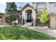 Inviting home entrance with arched doorway, manicured lawn, and brick facade, creating a welcoming curb appeal at 9629 Silent Hills Ln, Lone Tree, CO 80124