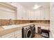 Well-equipped laundry room with sink, counter space, storage cabinets, and modern washer and dryer set at 9629 Silent Hills Ln, Lone Tree, CO 80124