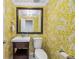 Stylish powder room with yellow and white wallpaper, dark wood vanity, white sink, toilet, and decorative mirror at 7422 E 7Th Ave # 14, Denver, CO 80230