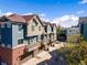 Townhome complex featuring brick and siding exteriors, private garages, and small balconies at 7422 E 7Th Ave # 14, Denver, CO 80230