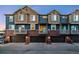 Townhome garages with balconies, brick trim, and cozy lighting showcasing home's exterior at 7422 E 7Th Ave # 14, Denver, CO 80230