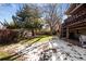 Large backyard with grassy area, mature trees, and deck; winter scene at 7107 E Costilla Dr, Centennial, CO 80112