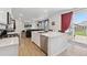 Open kitchen and living space includes a center island, white cabinetry, and outdoor access at 13221 E 110Th Pl, Commerce City, CO 80022