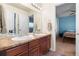 Bathroom with double sinks, granite countertop, wood cabinetry, and a view to the bedroom at 9515 E 109Th Cir, Commerce City, CO 80640