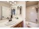 Bright bathroom features a wooden vanity, white countertops, and a shower/tub combo with tiled walls at 7452 S Utica St, Littleton, CO 80128