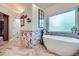 Bright bathroom features a freestanding tub, marble accents, and stylish herringbone floors at 7452 S Utica St, Littleton, CO 80128