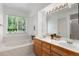Bathroom with a dual sink vanity, a large mirror, and a bathtub with a large window overlooking the yard at 12502 E Harvard Cir, Aurora, CO 80014
