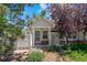 Inviting home featuring a well-manicured yard, mature trees, and a charming front entrance with white pillars at 12502 E Harvard Cir, Aurora, CO 80014