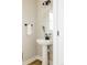 Half bathroom featuring a white pedestal sink, oval mirror, and modern black fixtures at 6303 Elmira St, Denver, CO 80238