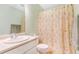 Bright, clean bathroom features white vanity and toilet, plus a shower with decorative floral curtain at 5320 E 100Th Dr, Thornton, CO 80229