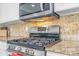 Kitchen features stainless steel gas range and microwave, granite counters, and a decorative tile backsplash at 5320 E 100Th Dr, Thornton, CO 80229