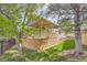 Grassy backyard with mature trees surrounding a covered patio with stairs to yard at 29 Woodland Cir, Highlands Ranch, CO 80126