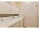 Laundry room with a white washer and dryer and ample overhead cabinet storage space at 29 Woodland Cir, Highlands Ranch, CO 80126