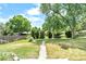 Well-manicured front lawn with a concrete walkway and mature trees enhancing the property's curb appeal at 6500 W 32Nd Ave, Wheat Ridge, CO 80033