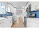 Modern kitchen featuring stainless steel appliances, white cabinets, blue backsplash and hardwood floors at 6500 W 32Nd Ave, Wheat Ridge, CO 80033